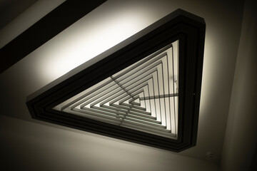 Triangular light source. Lamp in interior. Designer light. Architecture details.