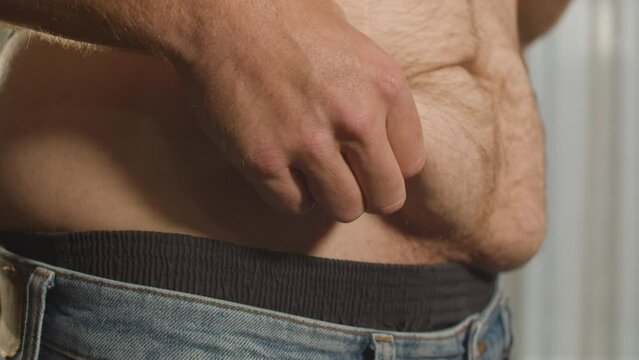 Close up of Shirtless man grabbing belly fat from love handles - side view