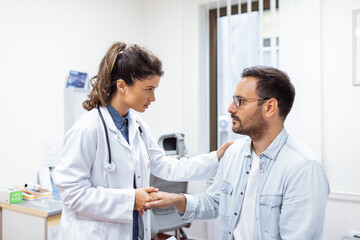 Young female doctor hold hand of caucasian man patient give comfort, express health care sympathy, medical help trust support encourage reassure infertile patient at medical visit