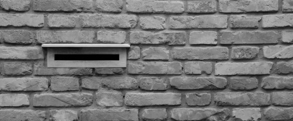 Mailbox walled into an old brick wall of an old house, black and white