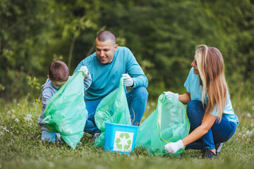 Mother and father teach their son to recycle plastic in recycling containers. They volunteer in a...