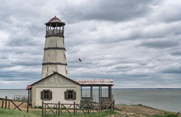 Old lighthouse building on sea shore at cloudy day