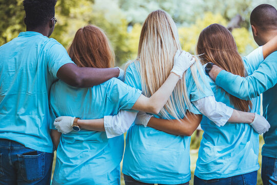 Rear View Of A Group Of Unified Volunteers Who Are Participating During A Community Cleanup Day.