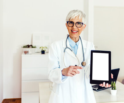 Portrait of confident female doctor showing digital tablet over white background. Portrait of a young medical practitioner holding up a digital tablet