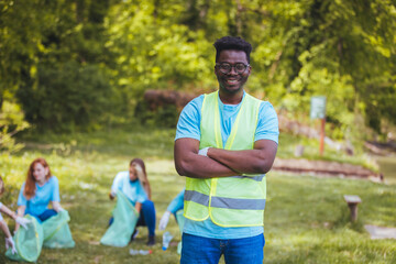 A young handsome African-American volunteers in a T-shirt keep your arms crossed and smiles cheerfully. Volunteer concept