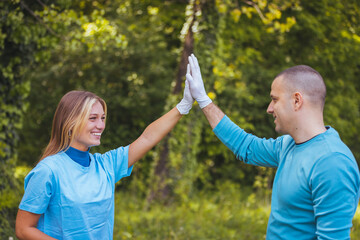 Yes, we did it! Proud young couple doing a high five after picking up all the trash from the park for their volunteer work....