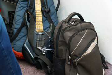 A black guitar, a case and a backpack are the musicians touring equipment in the room