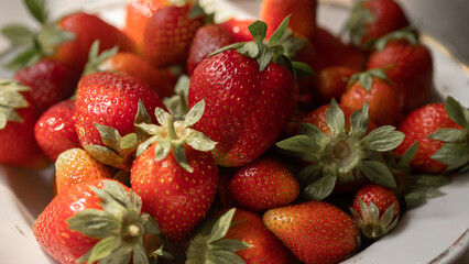 Strawberries on a plate. First summer harvest of strawberries. Fresh ripe strawberries background.