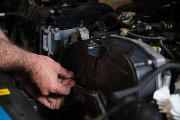 Auto mechanic hands unscrews the engine mount to replace the timing belt. Mechanics workshop.