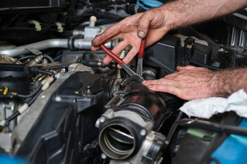 Car mechanic hands replacing engine throttle body. Mechanics workshop. - obrazy, fototapety, plakaty