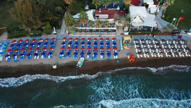 Aerial top down view of holiday relaxation spot of umbrellas and loungers on sandy beach in Kusadasi, Turkey.