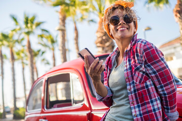 Cheerful trendy young adult woman use app mobile phone to plan and set next travel destination...