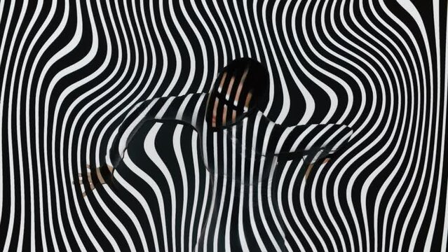 Young female model wearing bodysuit and futuristic eye glasses dancing overlay overlay black white twisted lines stripes background. Attractive woman on hypnotic backdrop illuminated with projector