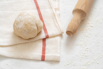 Rolling pin with dough on white background.