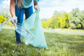 Students clean the local park, collect garbage in bags. On a beautiful sunny day, a group of young...