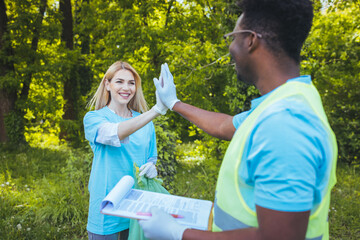 A group of young volunteers in a blue T-shirt pick and collect garbage from the forest. Volunteer...