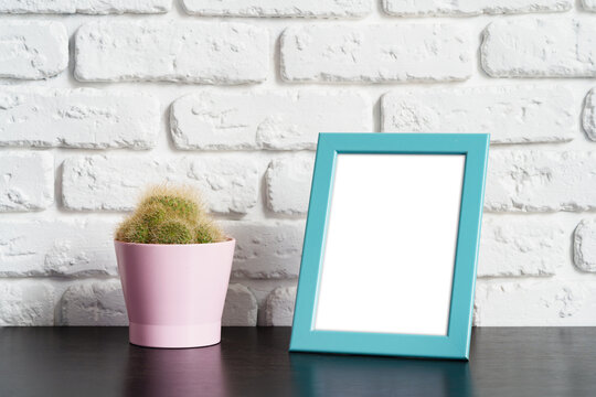 Wooden picture frame on a table with cactus