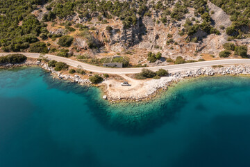 White Offroad Truck at the greek coastline with turquoise water in the foreground. Pelion Peninsula Greece.