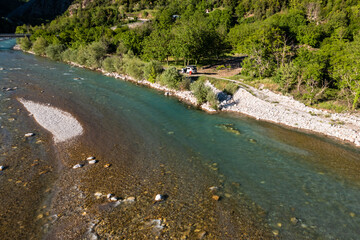 Camping with off road vehicle and roof tent on a wild mountain river with gravel bed in Greece 
