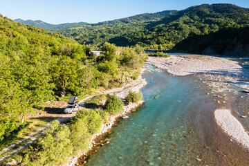 Camping with off road vehicle and roof tent on a wild mountain river with gravel bed in Greece 