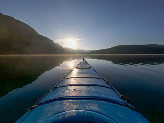 Kayak on Lake Zirou in Greece in the early morning hours with golden sunlight and morning fog