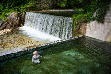 Blonde woman in swimsuit bathing in the hot springs of Loutra Pozar