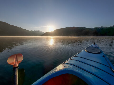 Kayak on Lake Zirou in Greece in the early morning hours with golden sunlight and morning fog