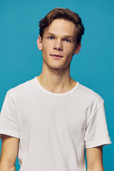 portrait of a handsome, cute guy in a white t-shirt on a blue background