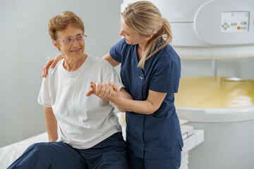 Radiologist help to patient sit after procedure of MRI or CT Scan . High Tech medical equipment