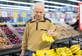 senor man pensioner buying banana in grocery in supermarket