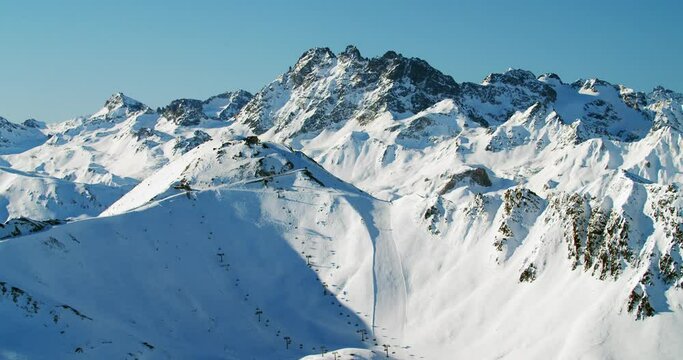 High alpine ski resort panorama view with big ski slopes and moder ski lifts in the austrian alps. Huge summit peaks with fresh snow and beautiful light above 3000 meter sealevel. 4K