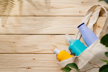 Sunscreen cream bottles in beach bag on wooden background