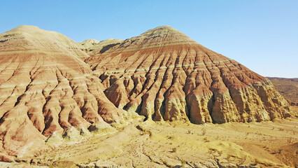 Colored mountains of Aktau in the steppe. Limestone mountains in the middle of the desert. Colored hills from white to red. The earth's rock is separated by layers. A huge canyon. Altyn Emel.
