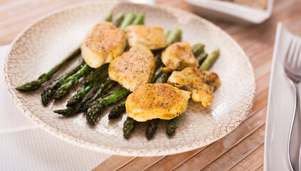 cooked dish. Chicken nuggets with green asparagus on plate
