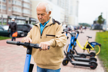 Portrait of mature man posing with electric scooter outdoor