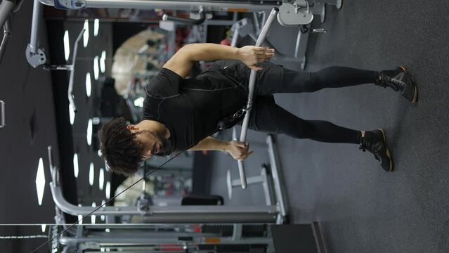Young man exercising on lateral pull at gym for the back mucles