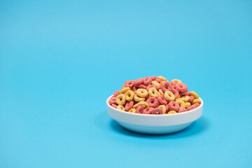 Fototapeta na wymiar Quick cereal breakfast in the form of rings on a plate on a blue background