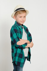 Portrait of cute stylish blond boy kid 7 years old wearing hat and checked shirt and jeans