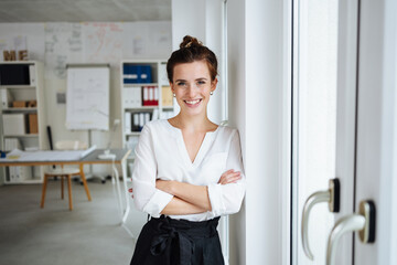 Confident young businesswoman looks at camera laughing