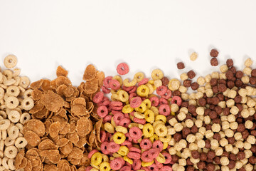 A set of different quick breakfast cereals - rings and balls, top view on white.