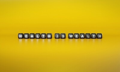 Words ‘Health is wealth’ spelled out in white text on dark wooden blocks against plain yellow background. 3D rendering