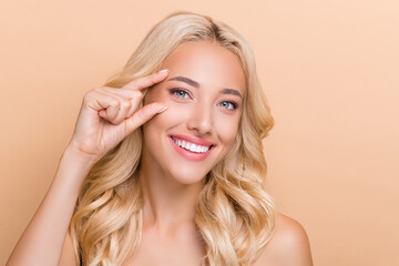 Portrait of attractive cheerful wavy-haired girl showing place injection uplift effect isolated over beige pastel color background