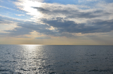 Sunlight reflections on the sea, sparkling water surface, blue sky with clouds, scenery