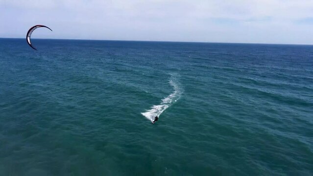 A person practicing kite surfing in the Mediterranean sea. A fun sports activity at the Spanish shoreline. A kite surfer in the waters outside Nerja on the Spanish coastline.