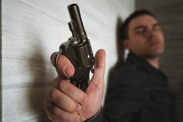 Threat to life. Close-up of hand with pistol. Shootout of criminals with revolvers. Killer or...