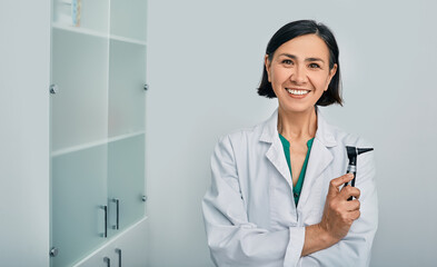 Woman audiologist with otoscope standing in medical clinic. Ear treatment and hear exam