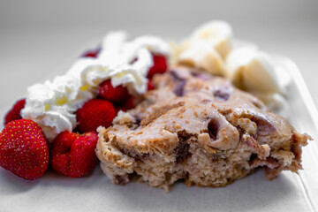 Strawberry quick bread with fresh strawberry fruits and banana with whip cream on top, close-up side view