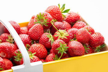 Ripe strawberries in a yellow cardboard box. Isolate on white background