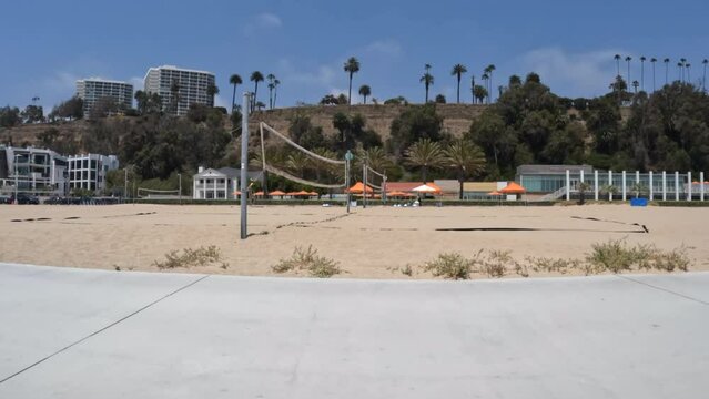 Moving view of volley ball nets, palm trees and beach park facilities near Santa Monica and Los Angeles, California.