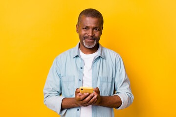 Portrait of positive person hold telephone blogging chatting isolated on yellow color background